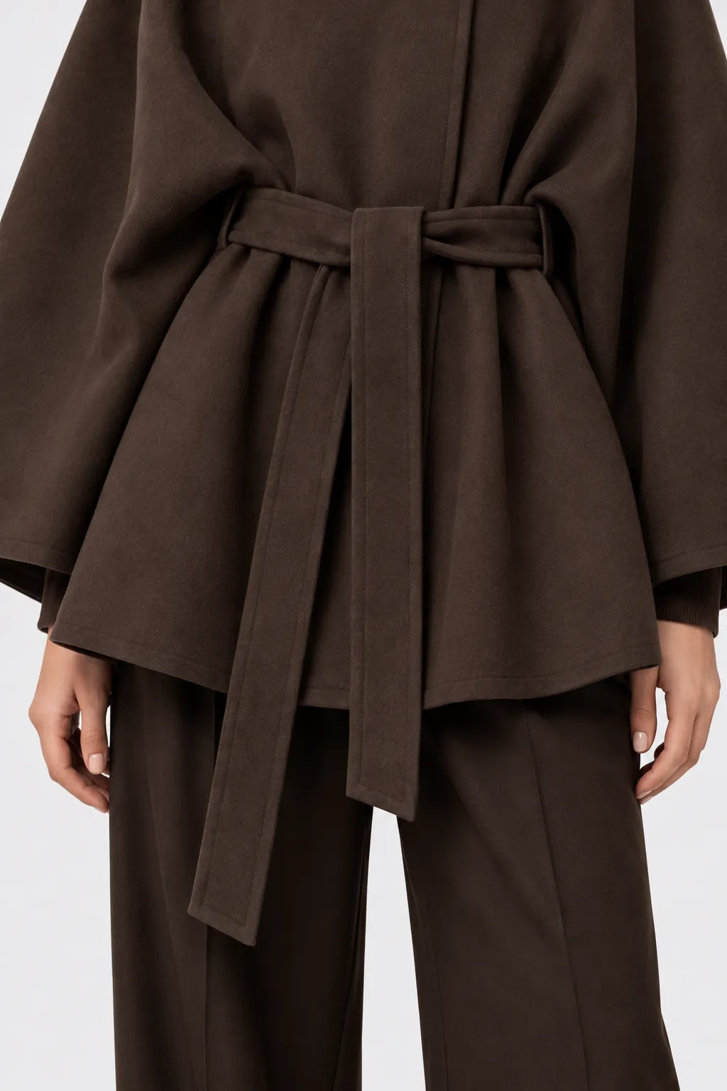 Détail de la ceinture à nouer et du drapé de la cape marron.