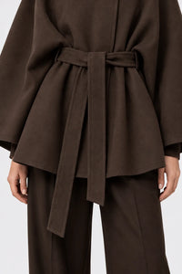Détail de la ceinture à nouer et du drapé de la cape marron.